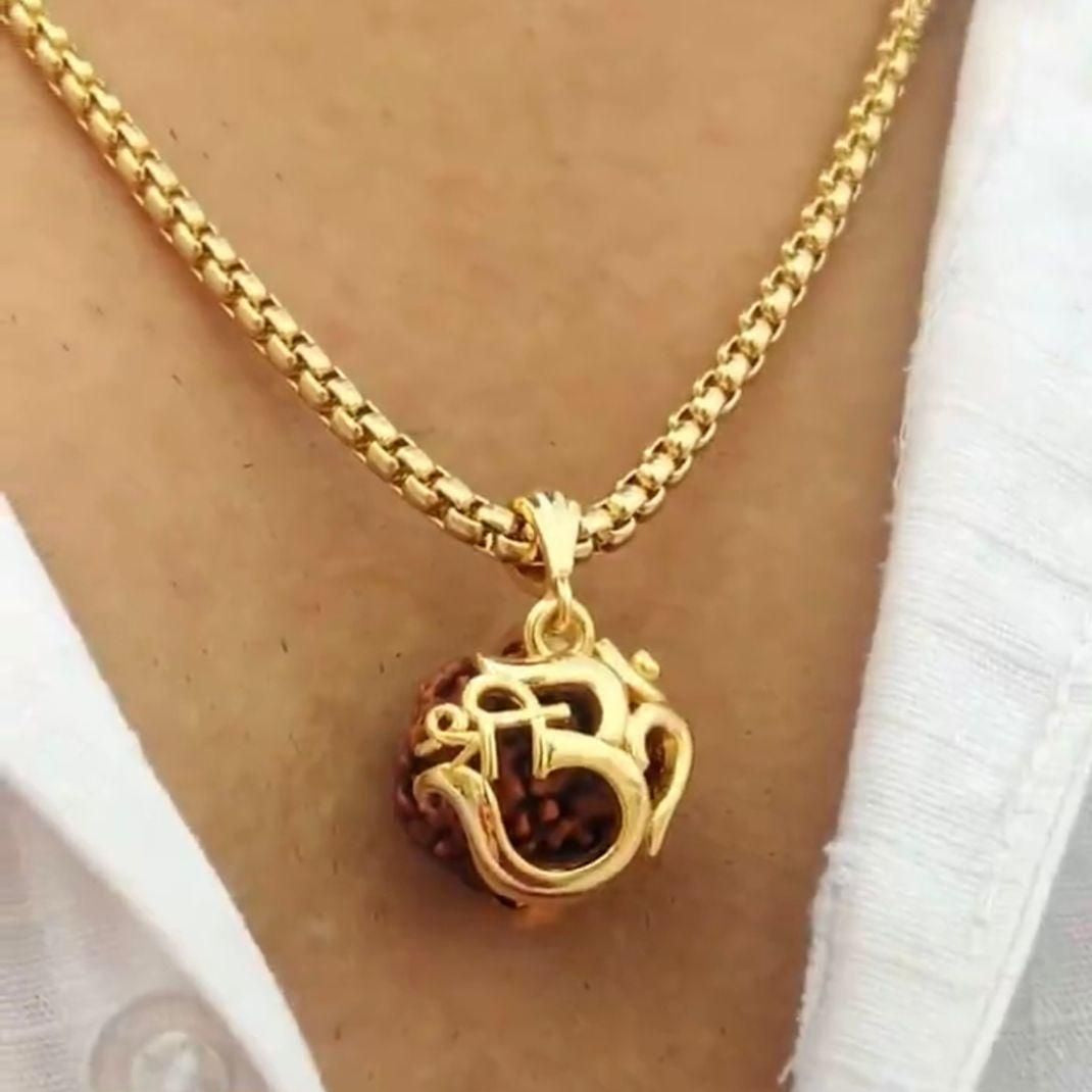 Gold necklace with a pendant worn by a person wearing a white shirt.